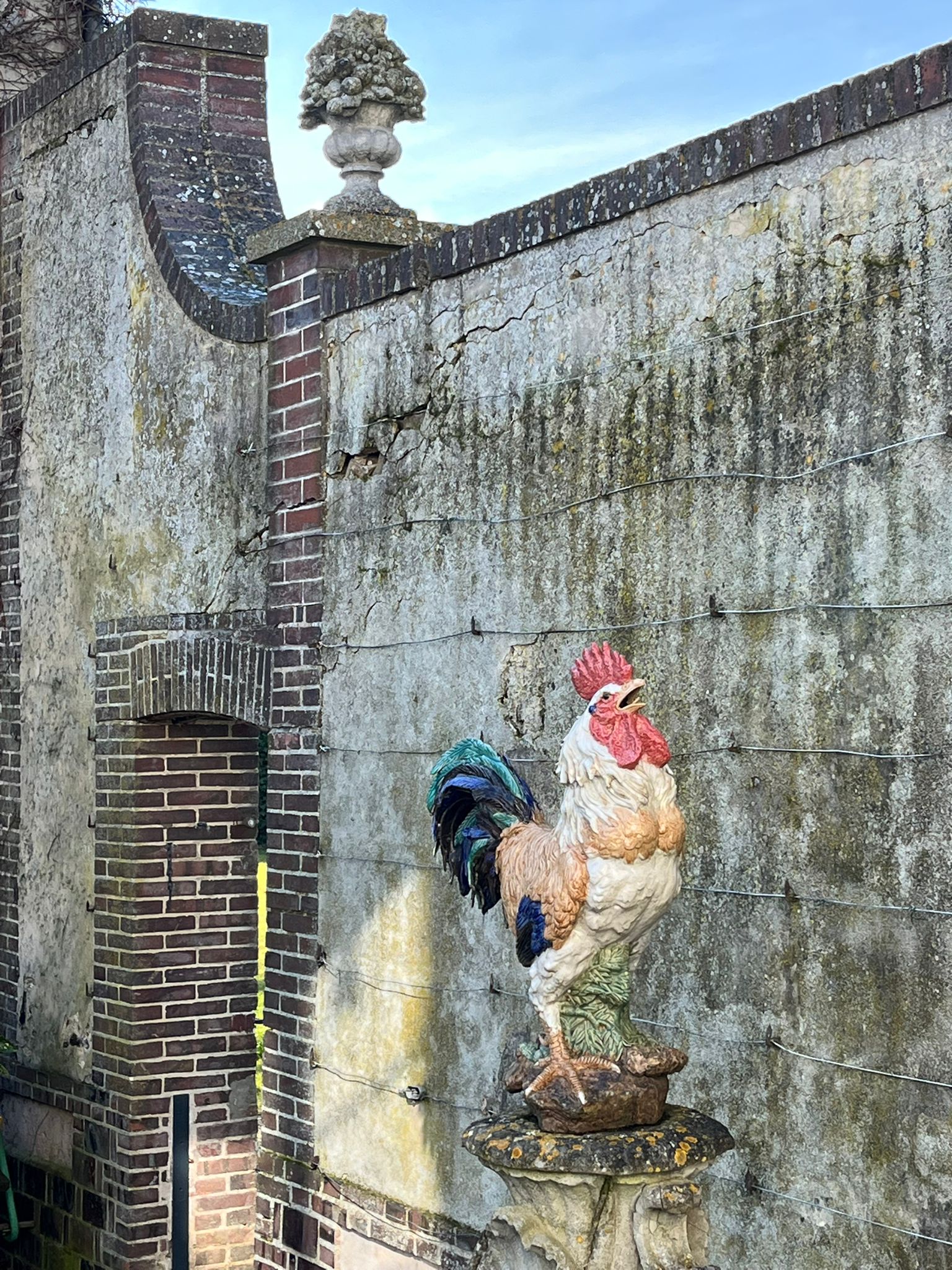Coq en céramique · mur de pierre · jardin clos